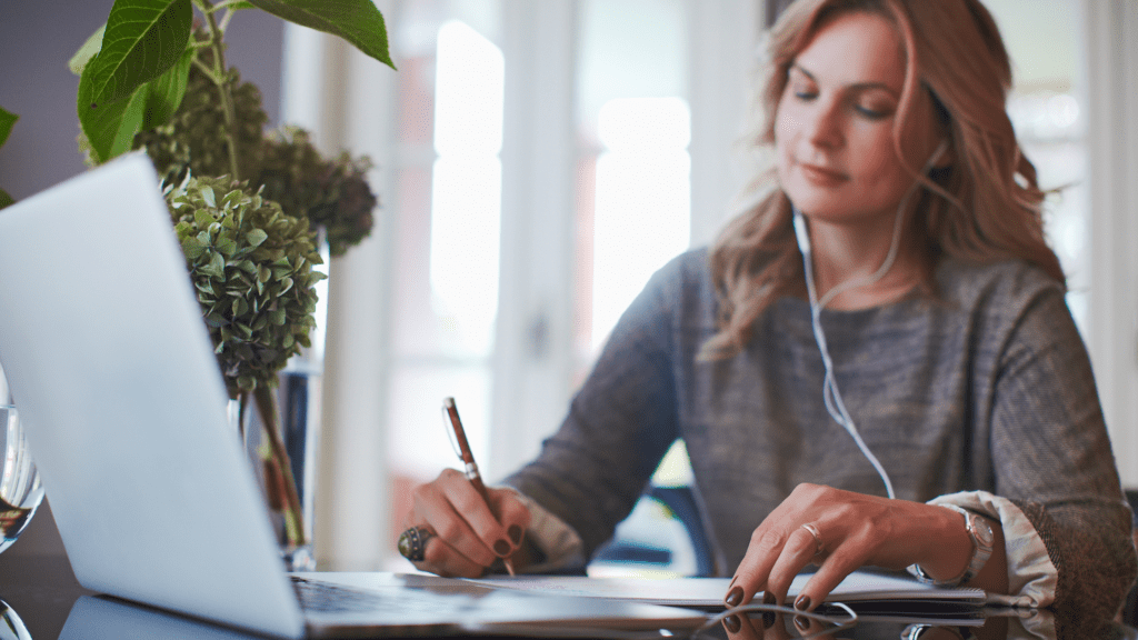 Eine Frau mit blonden langen Haaren arbeitet an einem Laptop im Home Office